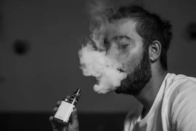 男子使用電子煙吐出煙霧,搭配日本梵茶鐵觀音煙油風味解析文章